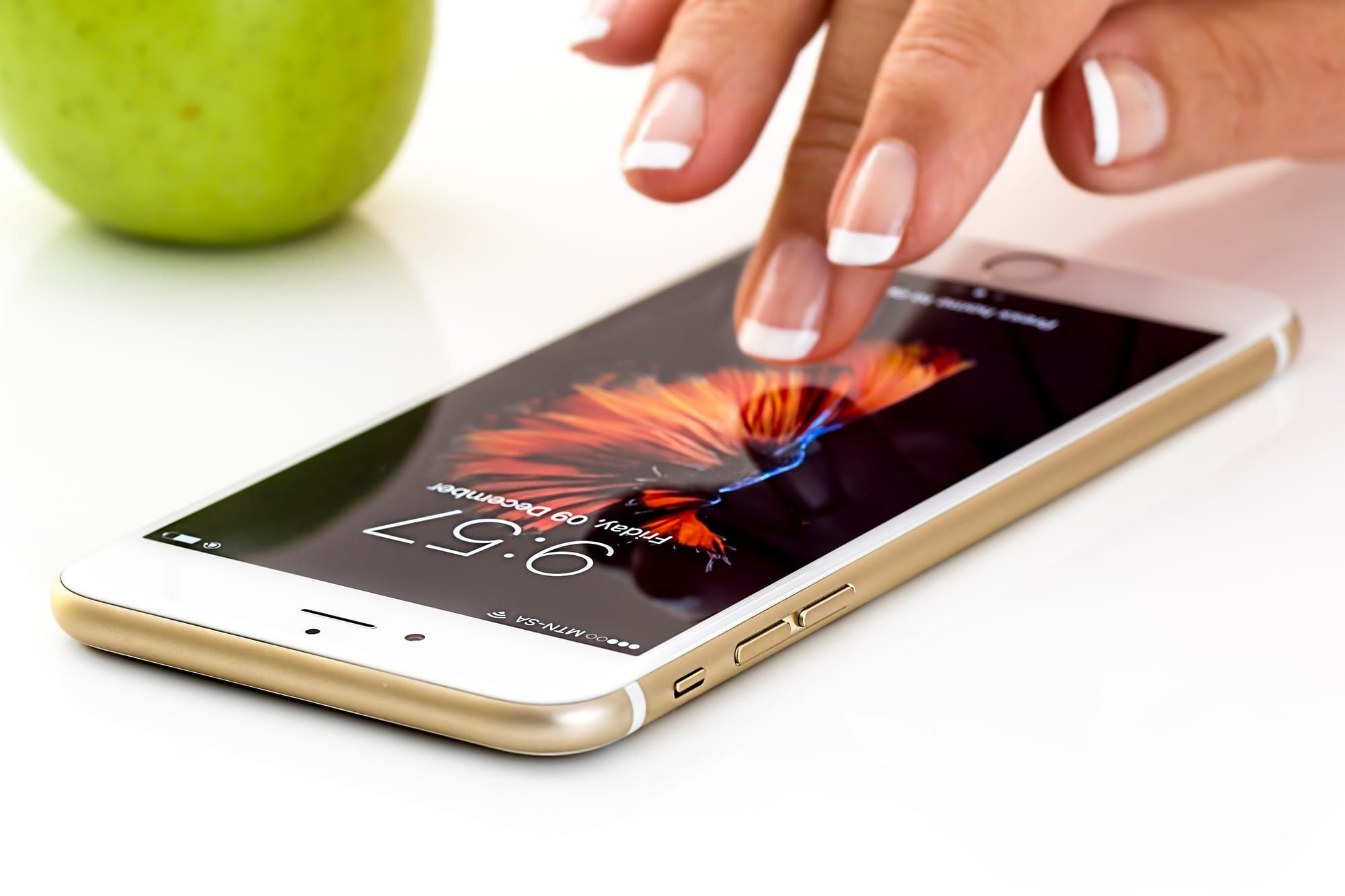A smartphone lying on a white table, its lock screen lit