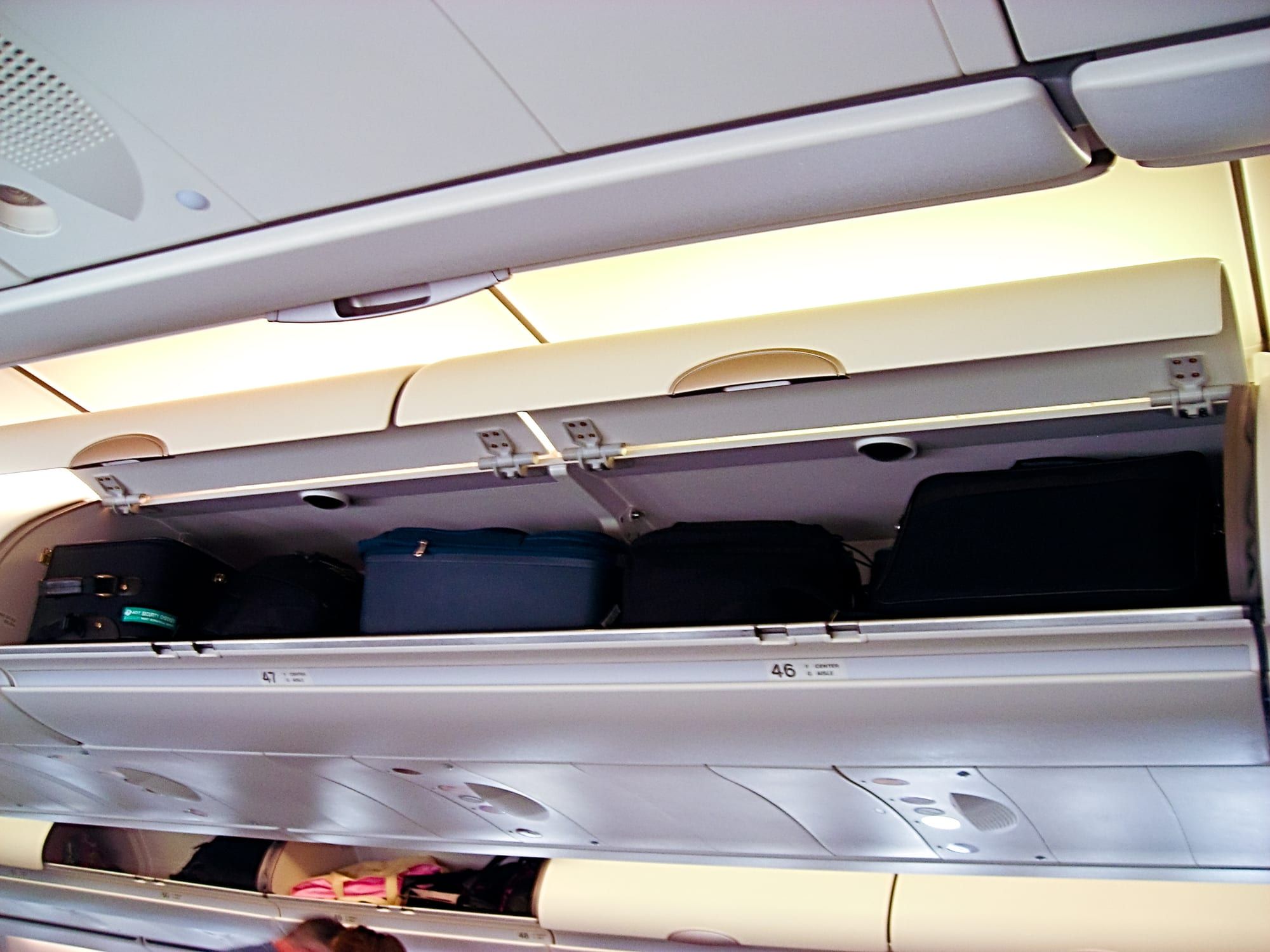 Open overhead bin on an airliner holding several carry-on bags