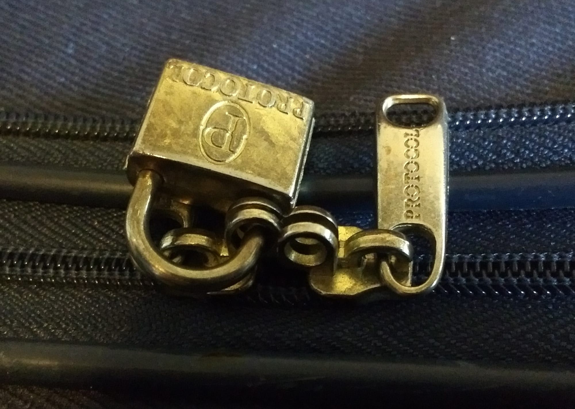 Close-up of a suitcase zip fastened with a small padlock
